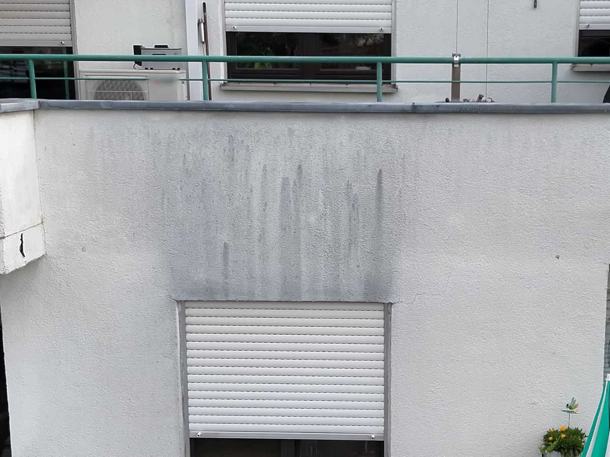 Dunkle Ablauffahnen auf einer Putzfläche unter der Attika