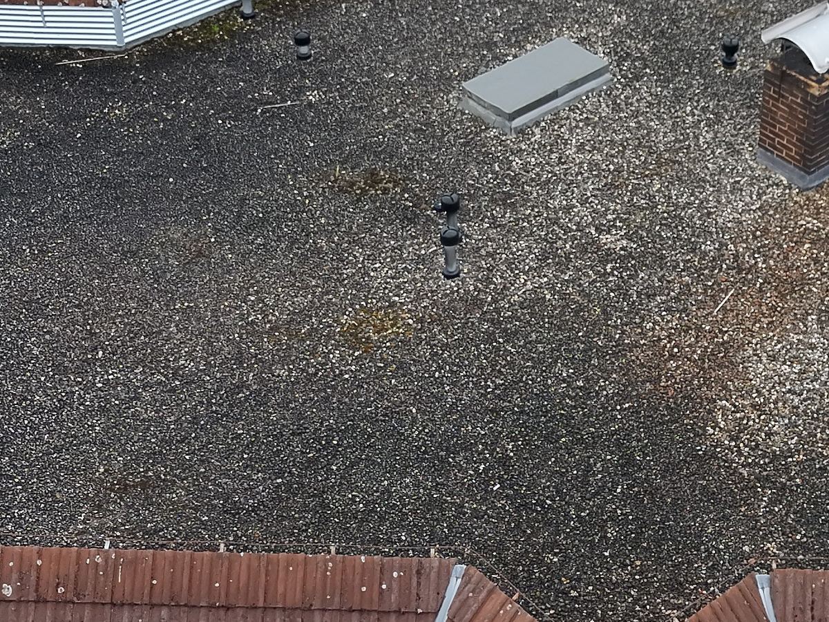Bekiestes Flachdach mit dunklen, bewachsenen Flächen