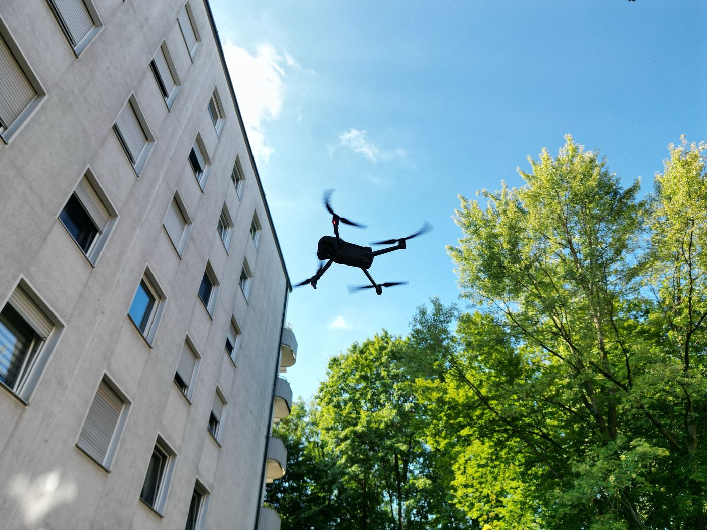 Drohne im Flug dicht vor der Fassade eines Wohnhochhauses