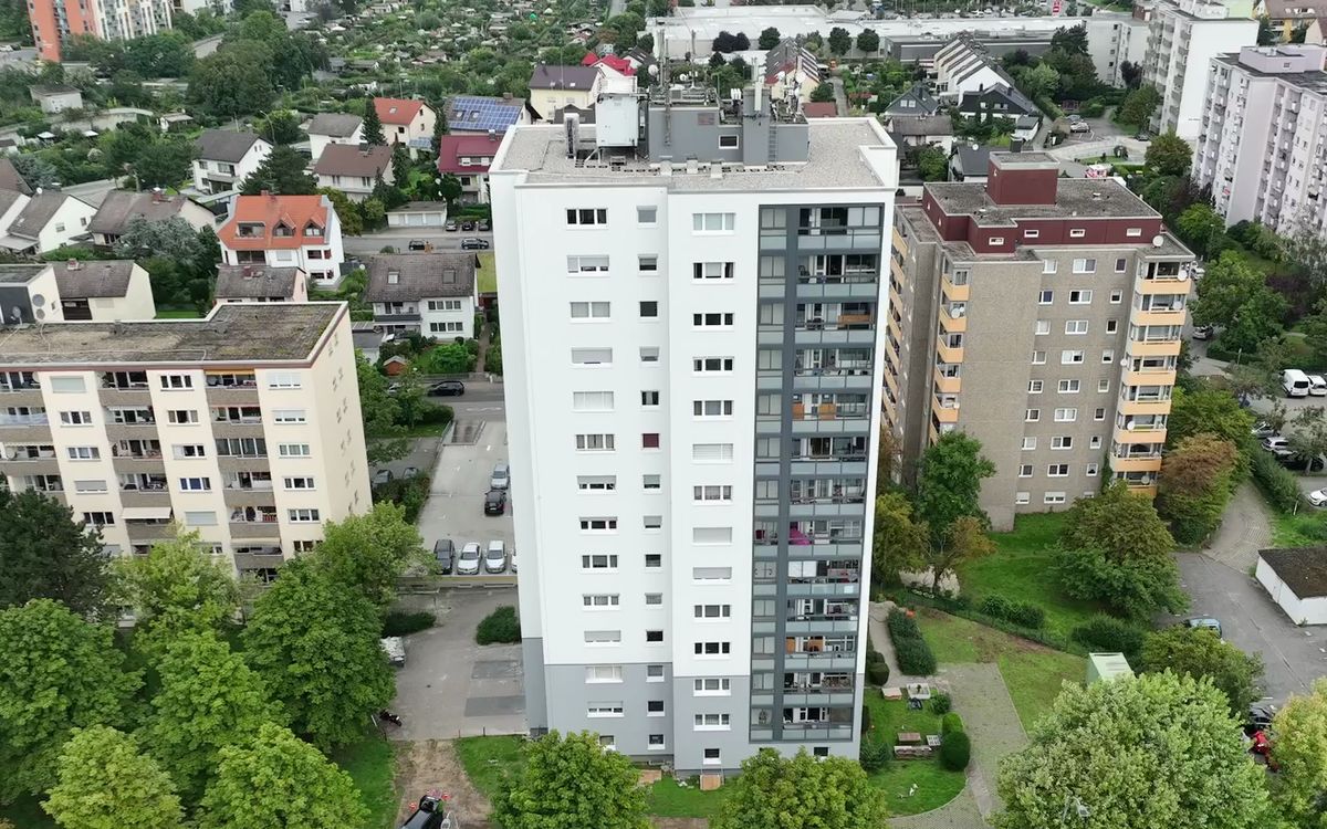 Luftaufnahme eines Wohnhochhauses zwischen kleineren Gebäuden